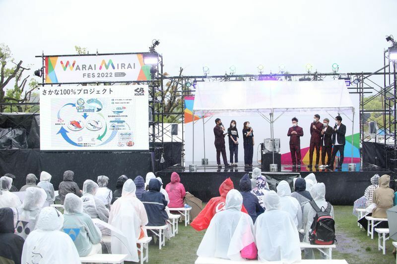 大雨のなかのW-zoneイベントステージで芸人のトークを楽しむ観客／写真提供：Warai Mirai FES2022