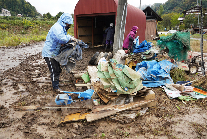 足滝地区の床上浸水した家屋の敷地で、泥にまみれた農機具などを運び出す住民たち（10月20日、筆者撮影）
