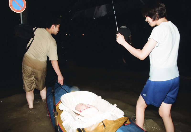雨が降り止まぬ中、ボートを引いて避難する藤岡さん夫妻（2000年9月12日、花井知之撮影）