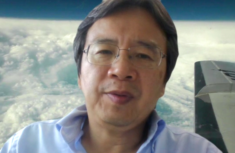 名古屋大学の坪木和久教授。取材はオンラインで実施。背景は2017年に坪木教授が航空機で直接観測したスーパー台風の画像