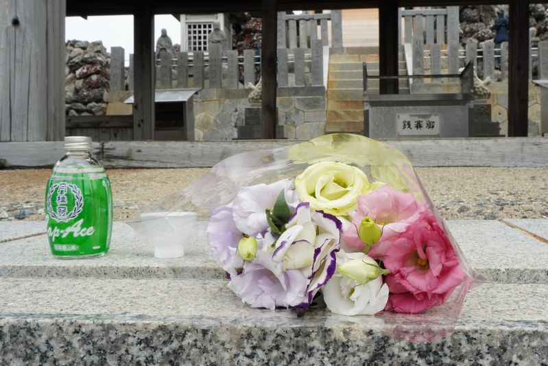 男性たちが御嶽神社で仲間に捧げた花束とお酒。この後、持ち帰って7合目の献花台に供えられた（筆者撮影）