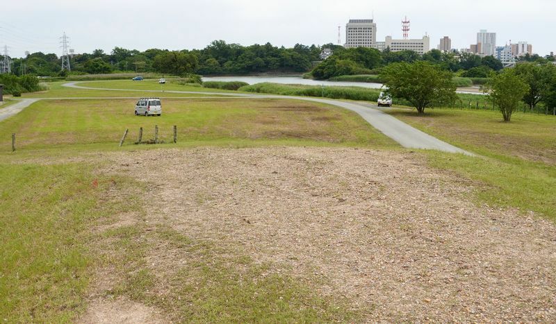 牛川霞堤の先端。堤防はなだらかに下る。奥に吉田城址の隅櫓や豊橋市役所のビルが見える（2021年5月、筆者撮影）