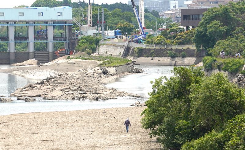 地元の人によれば、奥の堤防の下半分が白くなっているところが普段の水面の位置だという。手前の砂地は普段は川の下なので歩けない（2022年5月19日、筆者撮影）