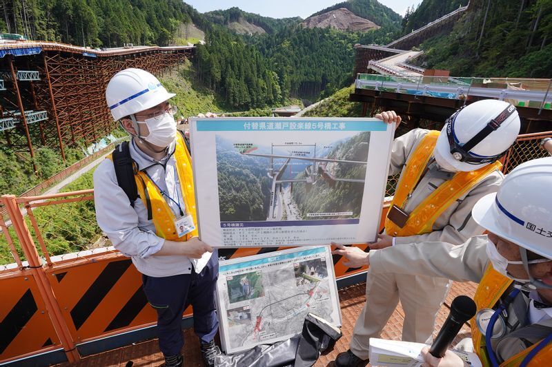 ダム本体手前に計画されている「付替道路」についても説明する担当者(2022年5月27日、筆者撮影)