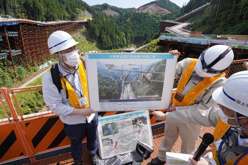 ダム本体手前に計画されている「付替道路」についても説明する担当者（2022年5月27日、筆者撮影）