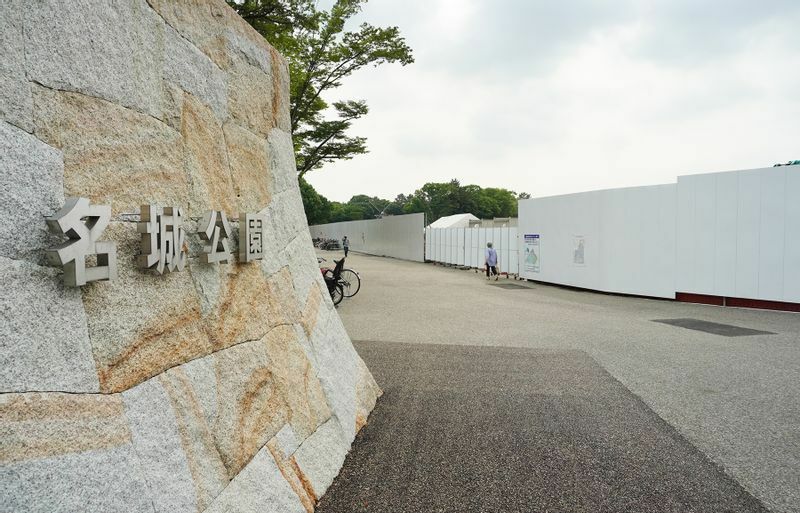 名城公園の入り口から白い工事塀で囲まれた愛知県新体育館の予定地を見る。この右手に大階段が設けられる（6月16日、筆者撮影）