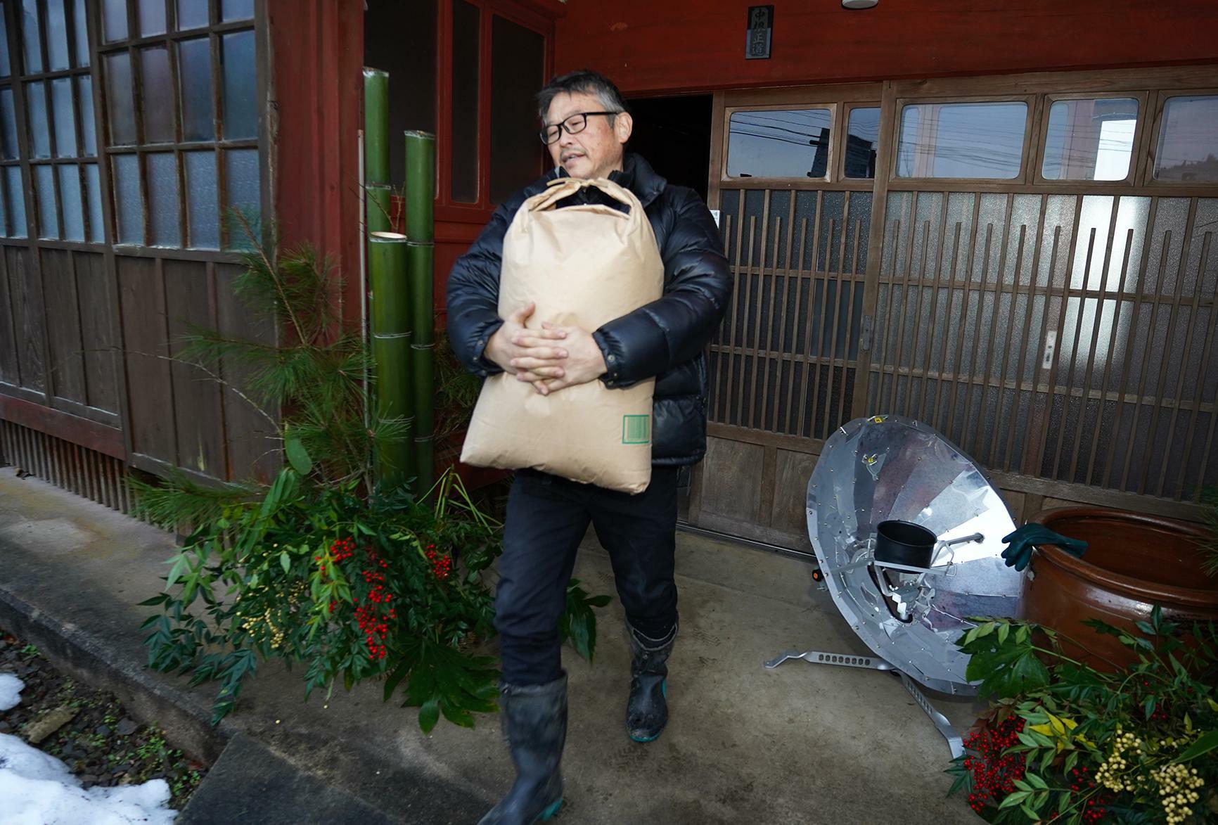 能登町内の離れに備蓄していた米を避難者に提供するため運び出す中根正道さん＝1月3日、筆者撮影