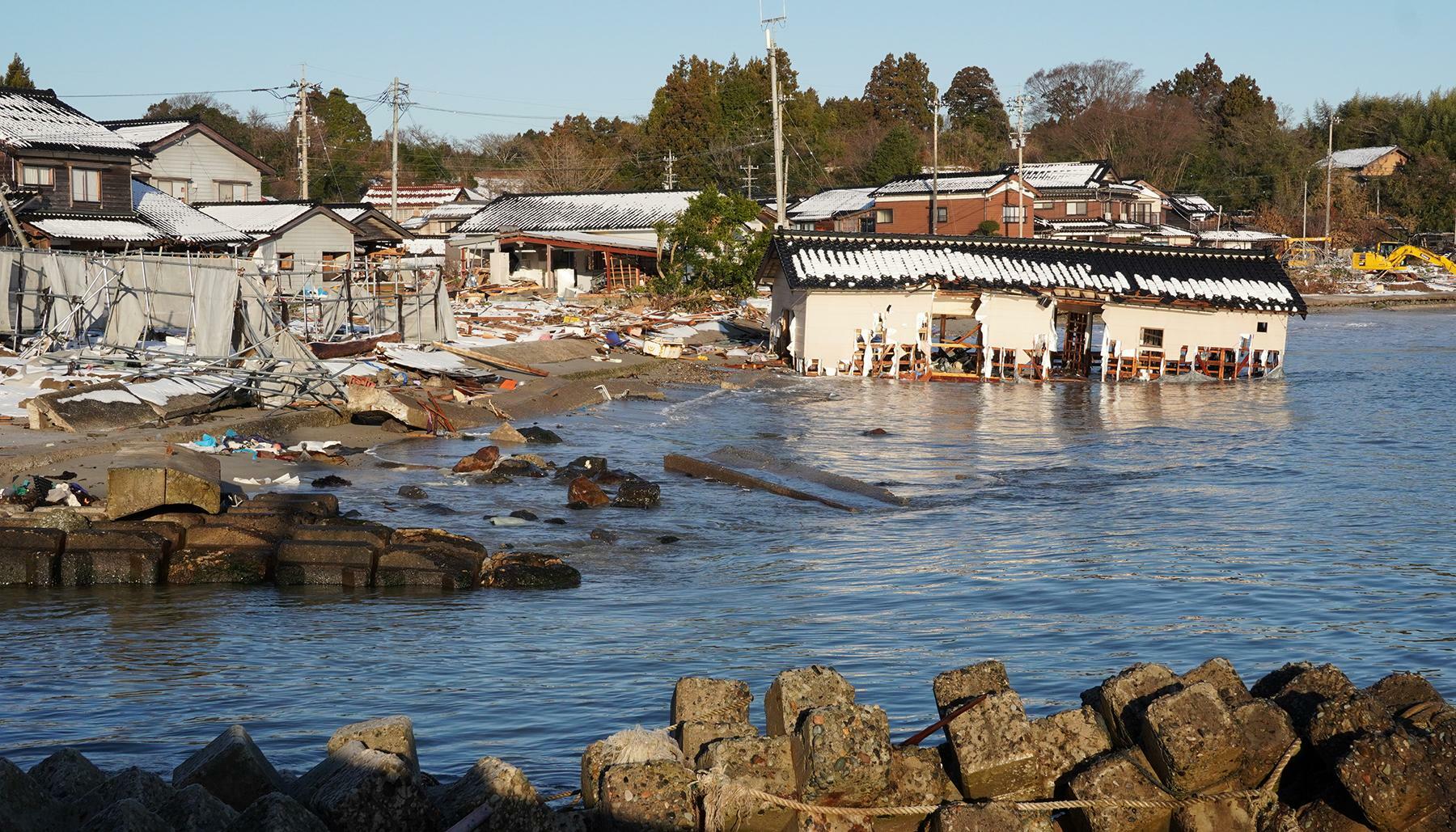 津波で瓦礫が散乱する能登町白丸地区。引き波で流されたとみられる建物が半分海に浸かっていた＝1月17日、筆者撮影