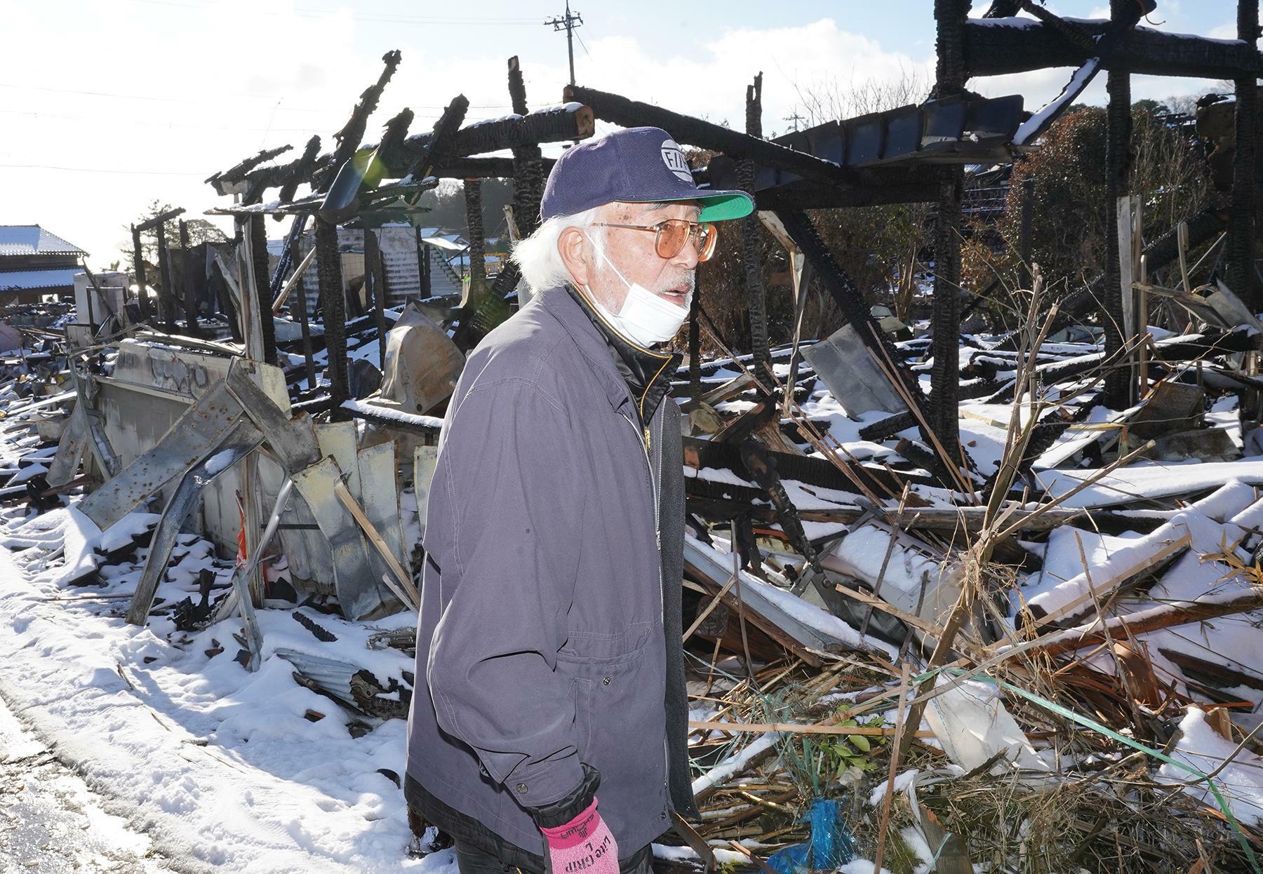 「火柱がバーンと上がった」と証言する縁山孝夫さん。自宅は全焼して黒い柱などを残すだけになってしまった＝1月17日、筆者撮影