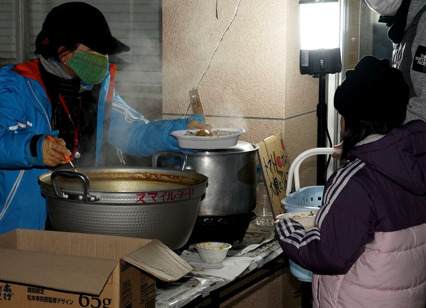 避難所で炊き出しのカレーを受け取る親子＝石川県珠洲市で、筆者撮影