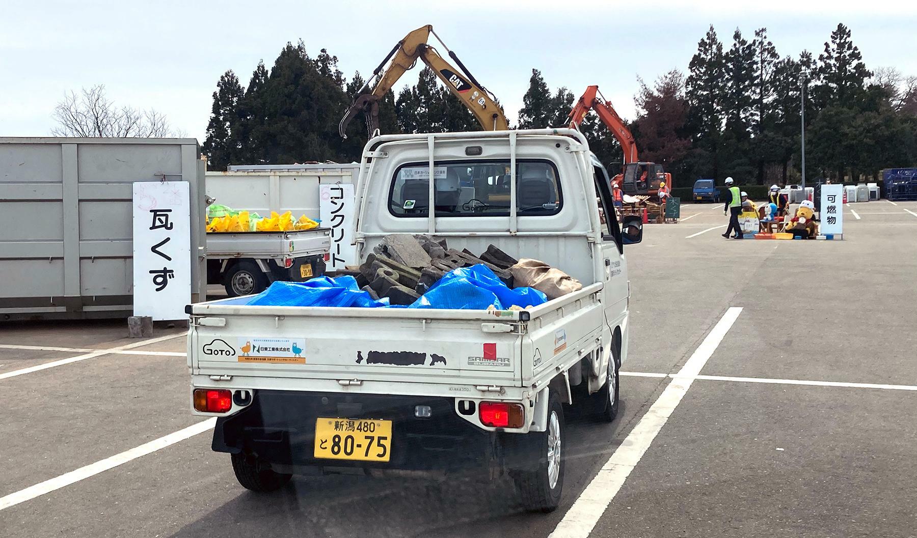 小木地区で軽トラに積み込んだブロックを藤波運動公園駐車場の災害ごみ仮置き場に運び込むまでが初日の活動でした＝4月11日、筆者撮影