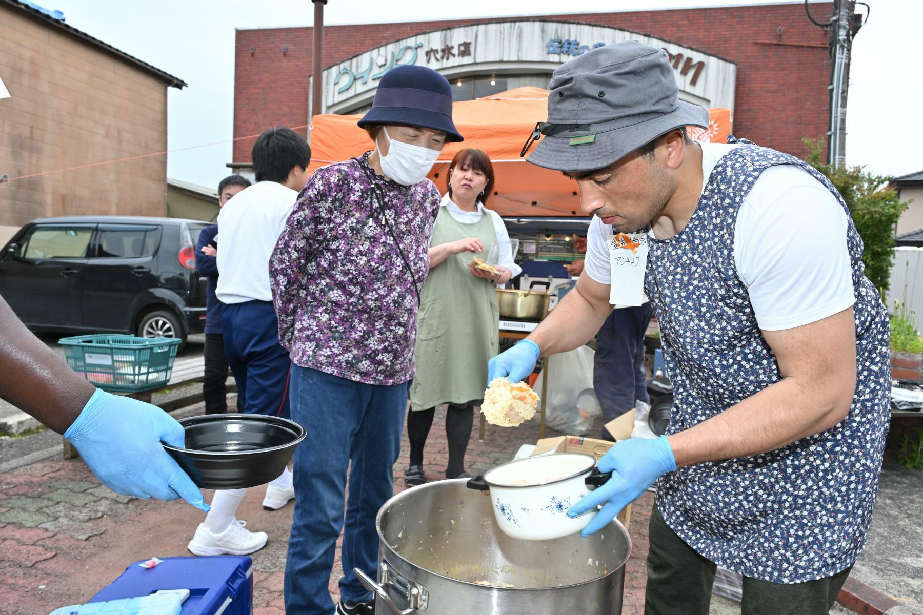 ウズベキスタンの炊き込みご飯「プロフ」作りに集中したアシュロフさん（右）＝5月6日、加藤直人撮影