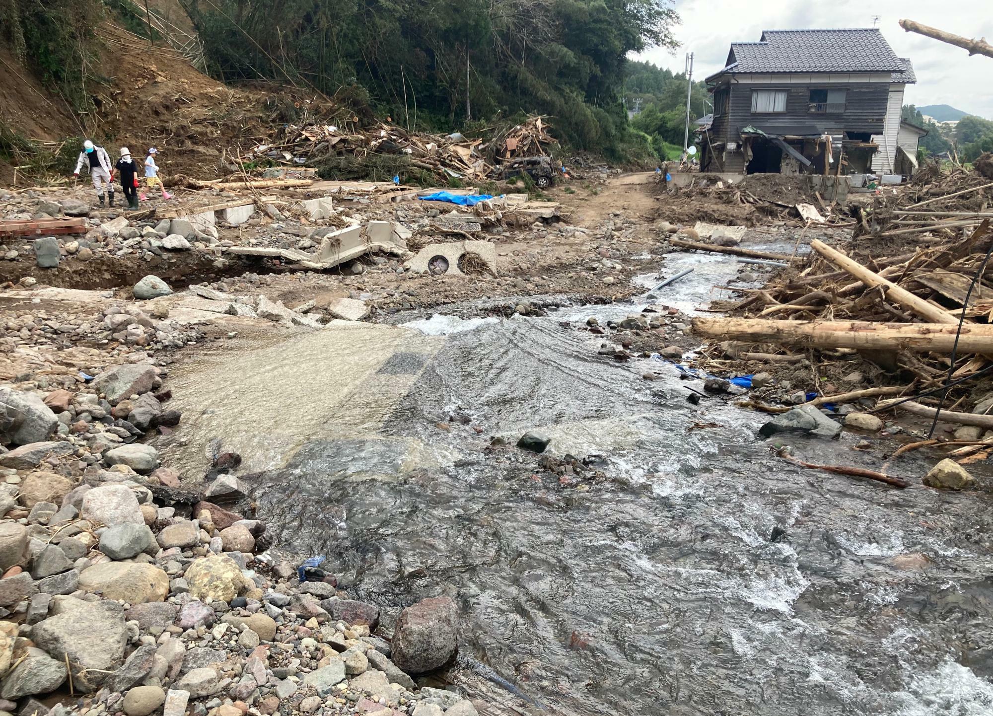 下流を振り返って撮影すると、左手に本来立ち並んでいた住宅がなくなっていることに気付く。右手の家も1階の壁がえぐれるような被害を受けていた＝9月28日、筆者撮影