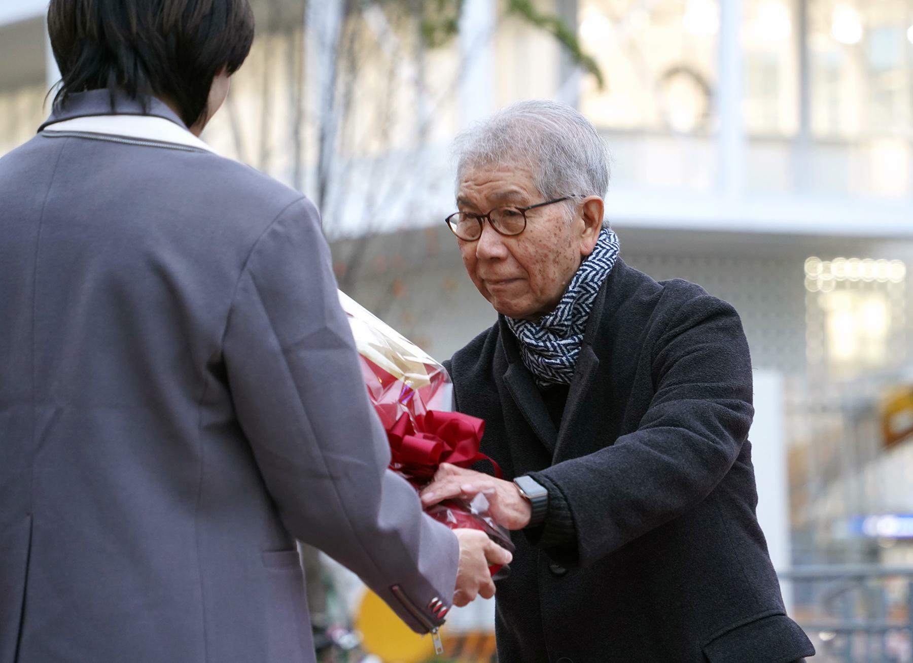 自身の設計した名古屋造形大のキャンパスを背に、学生からプリツカー賞受賞祝いの花束を受け取る山本理顕＝11月20日、筆者撮影