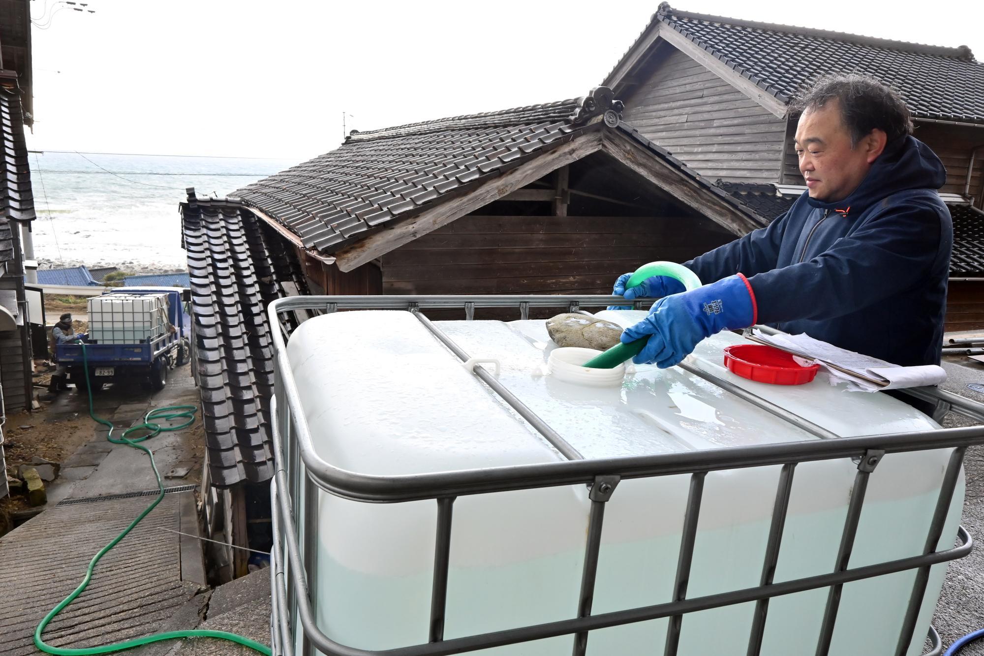 本間さんとペアで給水作業にあたる山本智之さん＝12月22日、加藤直人撮影