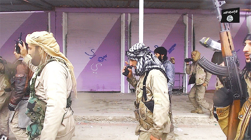 ISが公開した映像。シンジャル市内を歩く戦闘員の背後の店のシャッターにはスプレーで文字が書かれている。どれがヤズディかわかるよう区別するためだ。（2014年12月・IS映像）