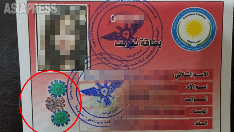 シリア北部コバニでは15日間の外出制限。公務の場合は特別カード（写真）があれば外出可。カード左下（赤枠）にはウイルスのイラスト。（コバニ住民女性提供）