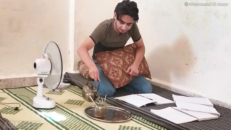 扇風機の横で勉強するフセイン君。（8月23日・イドリブ市内・撮影：ムハンマド・アル・アスマール）