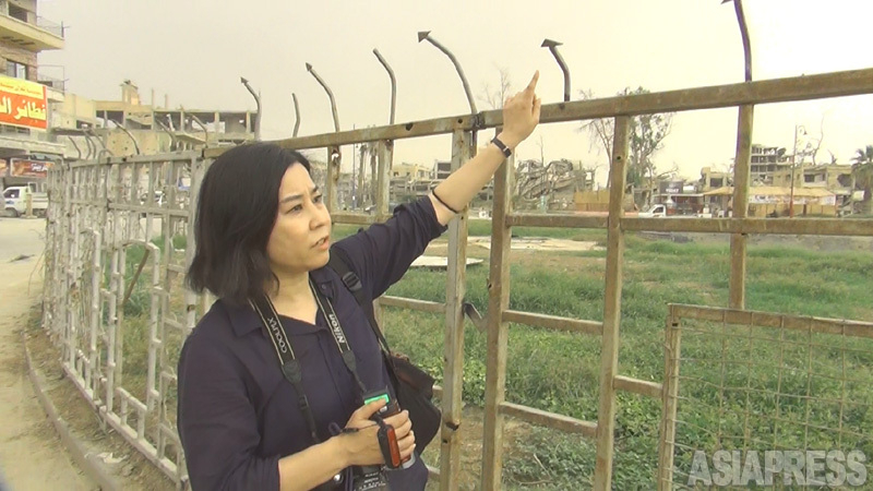 ラッカのナイム広場を取材する筆者。この鉄柵に斬首された生首がいくつも並べられた。（2018年10月・ラッカ・坂本卓撮影）