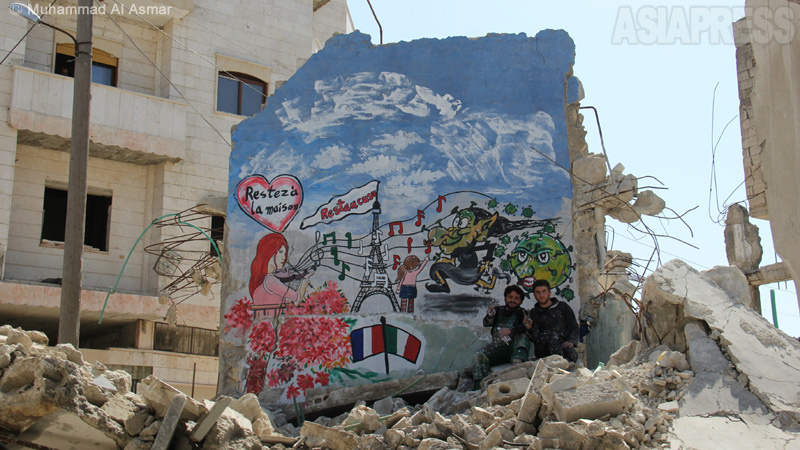 空爆や砲撃で激しく破壊された住宅地の壁の作品の前で。左がアジズ・アル・アスマールさん（48歳）。（2020年11月・撮影：ムハンマド・アル・アスマール）
