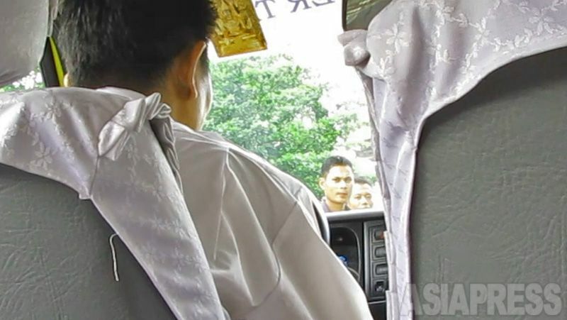 ウィンティンさんとタクシーに乗り込むと、私服警官（中央の２人）がこちらの動きを確認し、バイクで尾行してきた。（2010年10月ヤンゴン市内・玉本撮影）
