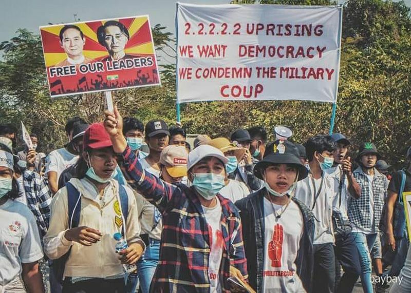 2021年2月に起きた国軍によるクーデターに抗議する市民。「我々は民主主義を求める。軍事クーデターを非難する」とのプラカードを掲げている。（2021年2月タニンダーイ管区ベイ市内・BayBay撮影）