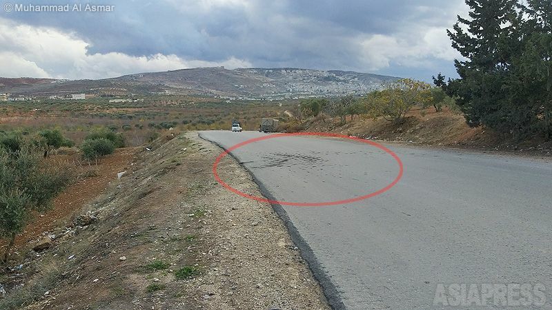 ドローンのミサイル攻撃の現場を地元記者に撮影してもらったもの。見通しのよい一本道で、周囲に遮蔽物はない。米軍は標的のバイクのわきに民間車両がいるのをわかっていてミサイルを発射したと見られる。赤枠がミサイル着弾現場。（2021年12月、シリア・イドリブ・撮影：ムハンマド・アル・アスマール）