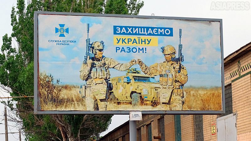 ロシア軍の侵攻後、ウクライナ軍や治安部隊を称える看板が目立つようになった。写真はウクライナ保安局のもので、男女の隊員が並び、「ウクライナをともに守る」とある。（2022年7月・オデーサ・撮影：玉本英子）