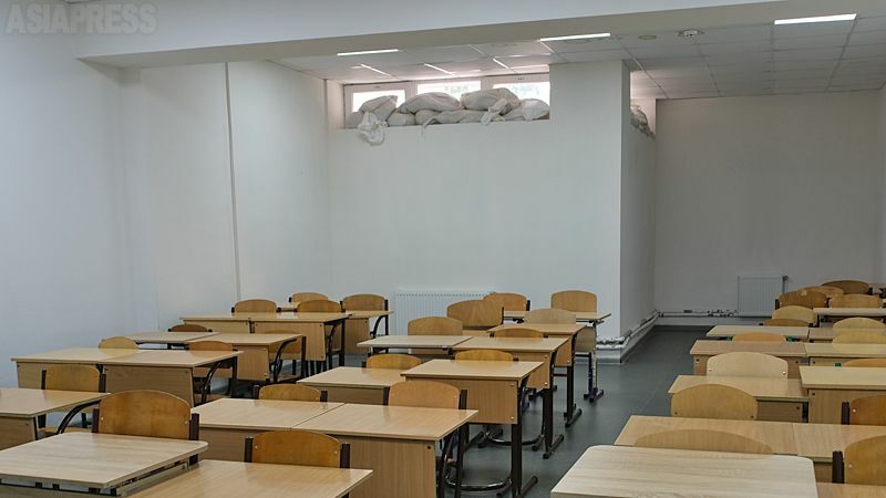 改修されたばかりの地下シェルター教室。地下に退避している時間でも授業ができるよう教室には机が並ぶ。半地下の窓に土のうが置かれていた。（2022年８月・オデーサ・撮影：玉本英子）