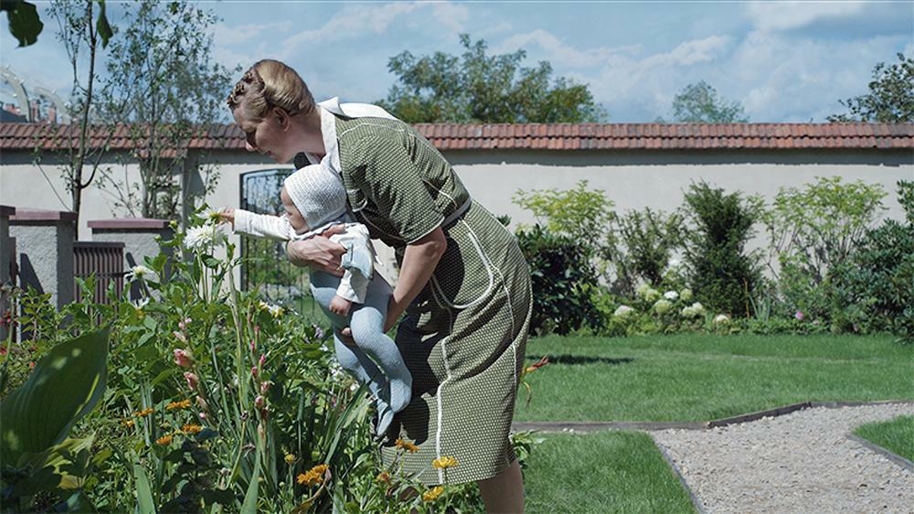ヘートヴィヒの関心は、子どもとの暮らし、庭の花、ようやく手にした幸福な家庭生活だけに向けられる。（映画『関心領域』・配給：ハピネットファントム・スタジオ）