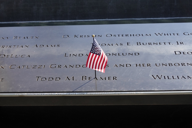 「9.11 メモリアルミュージアム」に隣接した記念碑には、犠牲者の氏名のが彫られた箇所に星条旗があった＝2019年7月（筆者撮影）