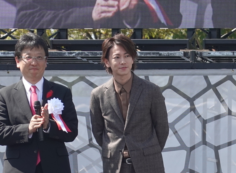 俳優の佐藤健さんの登場に式典会場は歓声に包まれた。左は大西市長