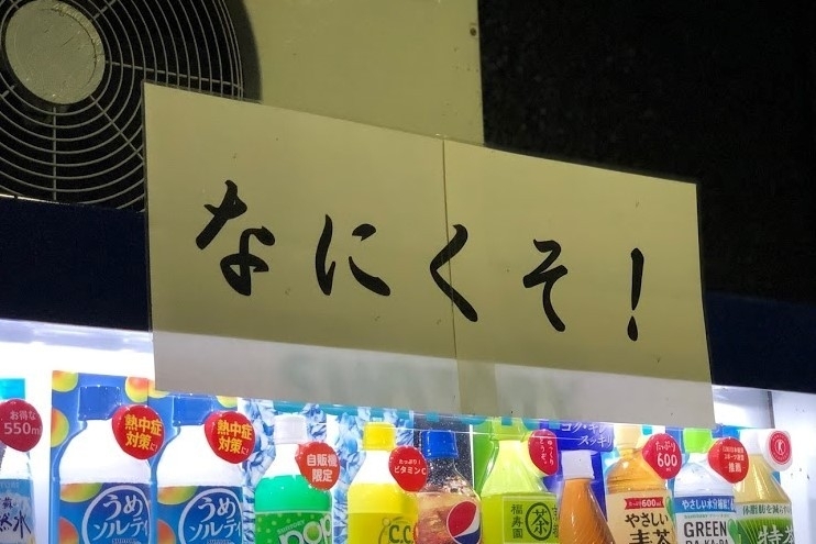 人吉市中心市街地の飲食店の前に置かれた自動販売機には、「なにくそ！」と書かれた紙が貼ってあった。新型コロナウイルス感染症と豪雨災害によって街は苦境に立たされている＝人吉市