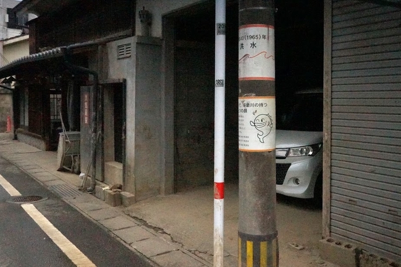 渕田酒造場のすぐわきにある電柱には、過去に水害があったことを知らせる表示があった＝人吉市
