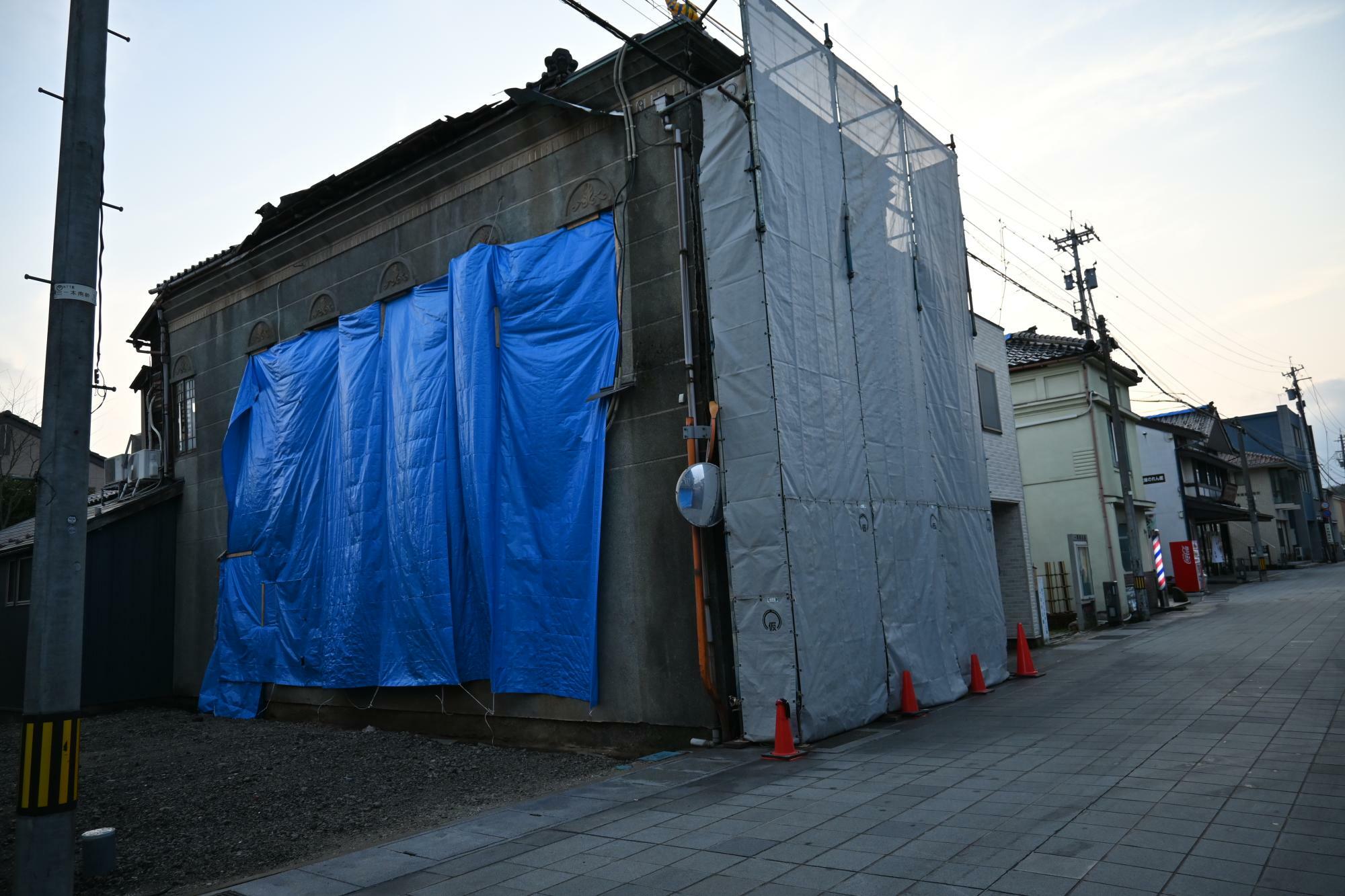 地震で外壁がはがれ落ちてしまった「一本杉 川嶋」。左隣りにあった宿泊施設の建設が始まっていた建物も危険なため取り壊され更地に（筆者撮影）