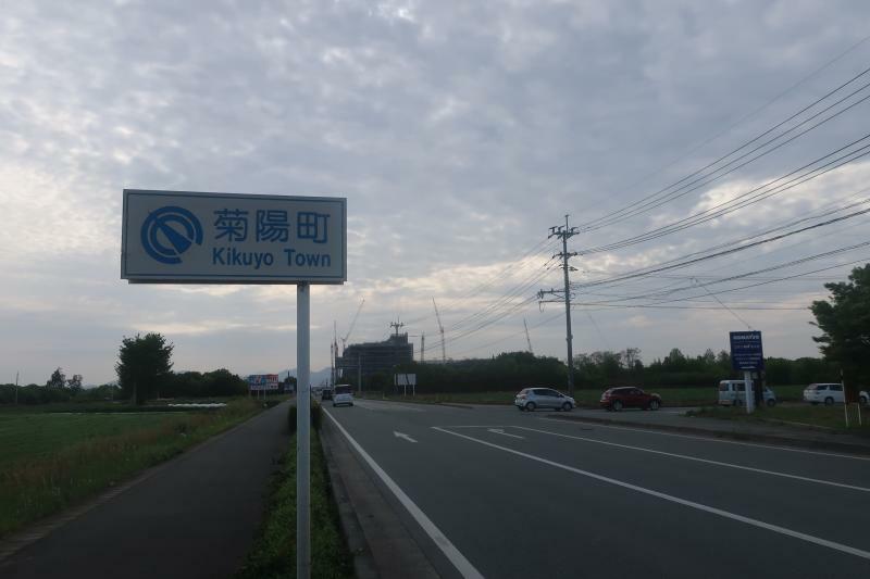 菊陽町に入ったことを示す標識と、件の建設中の工場。見ての通り、道路を挟んだ反対側は雑種地である。