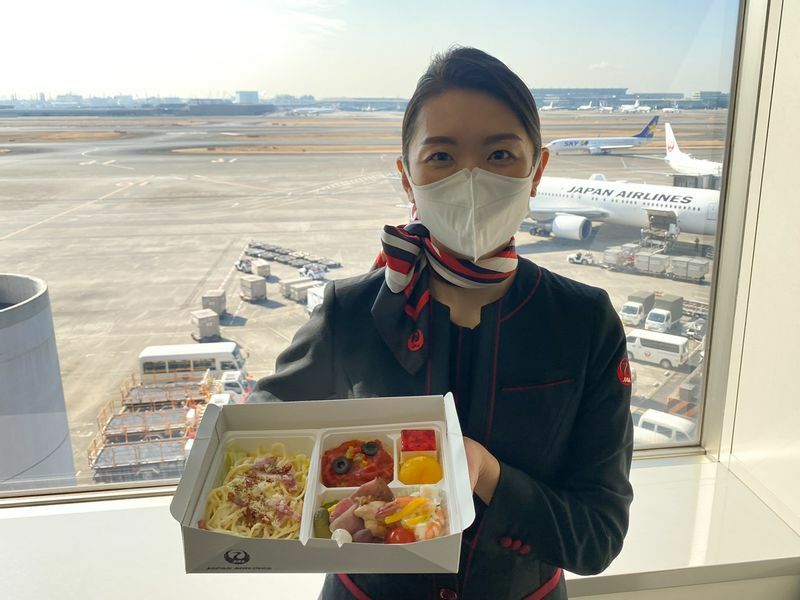 機内食風弁当（洋食）を持つJAL客室乗務員（2月3日、羽田空港にて筆者撮影）