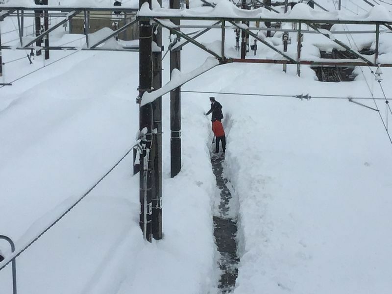 雪がやんだ時間を見はからって職員が線路わきの職員専用通路の除雪をしています。