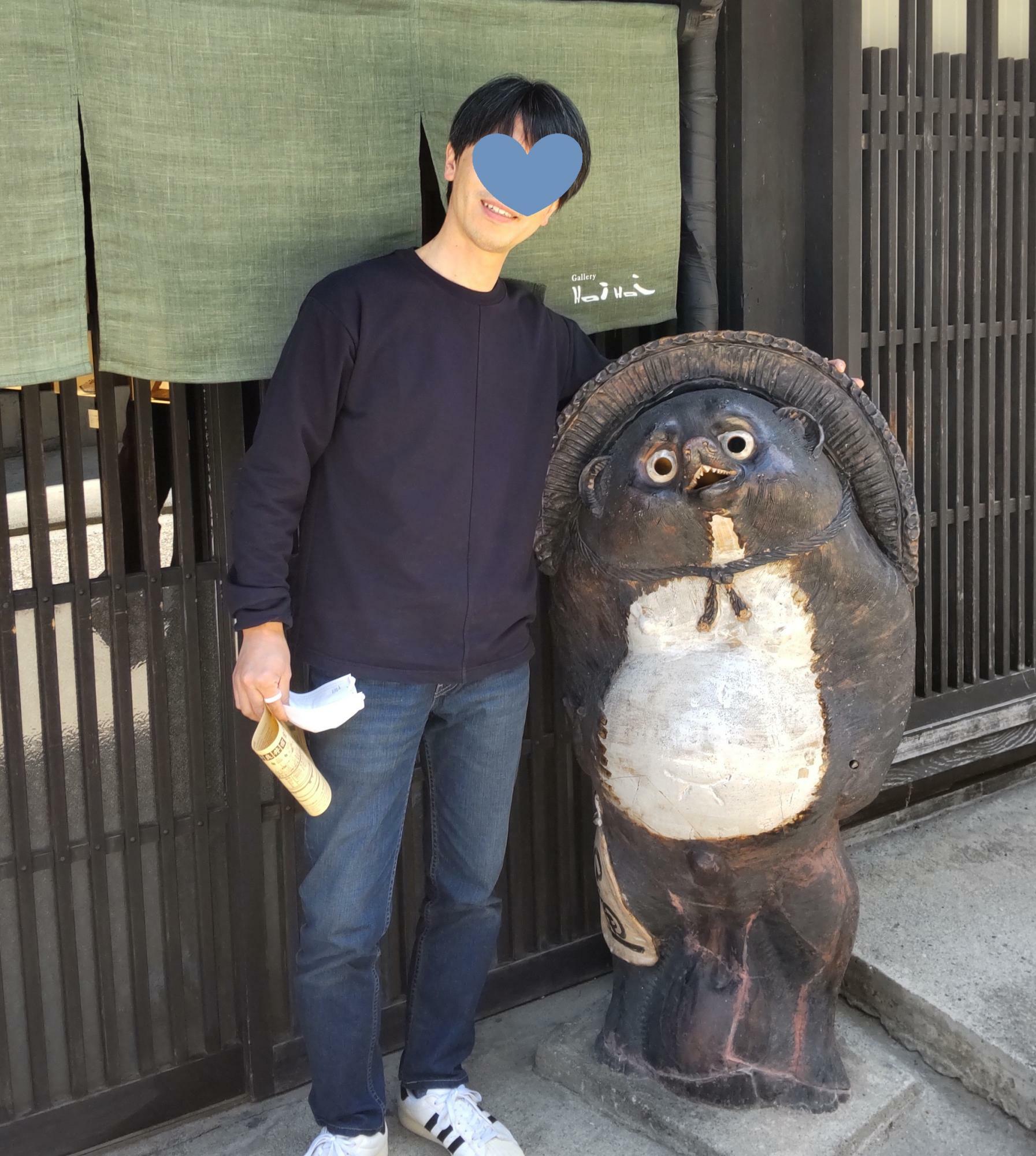 中山道の茶店でタヌキとツーショット。175センチ63キロの高田さん。憎めない感じの男性です。（本人提供）