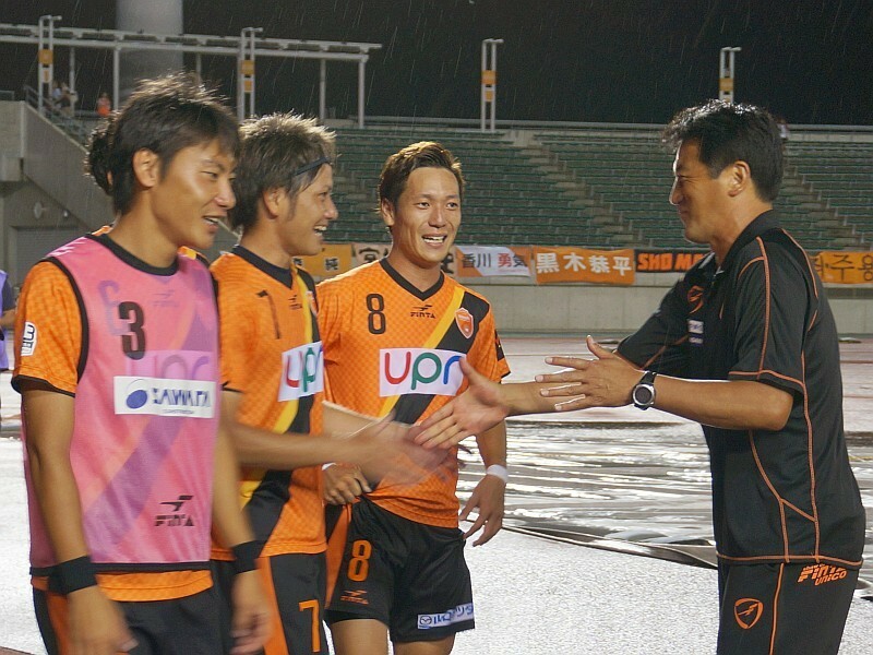 試合後、選手たちを出迎えて握手する上野展裕監督（右）