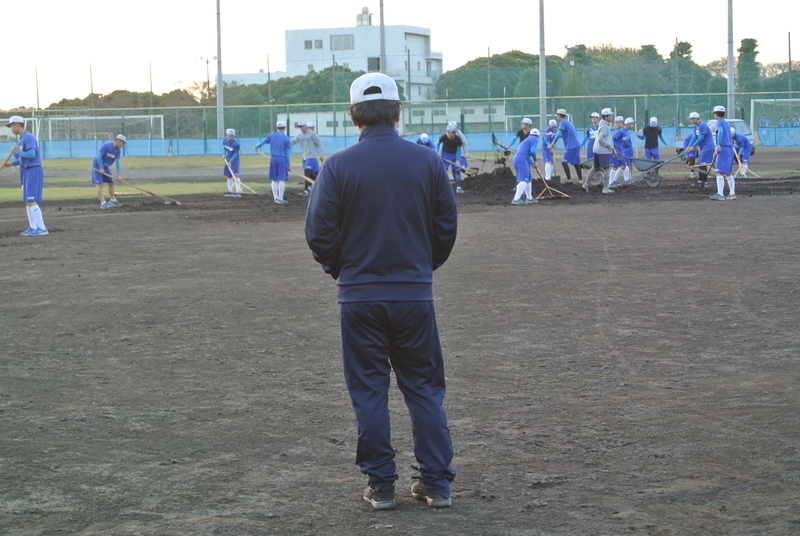 グラウンド整備をする選手を見守る岩井監督。「高校野球では取り組む姿勢や内面の成長が大事」と言う（筆者撮影）