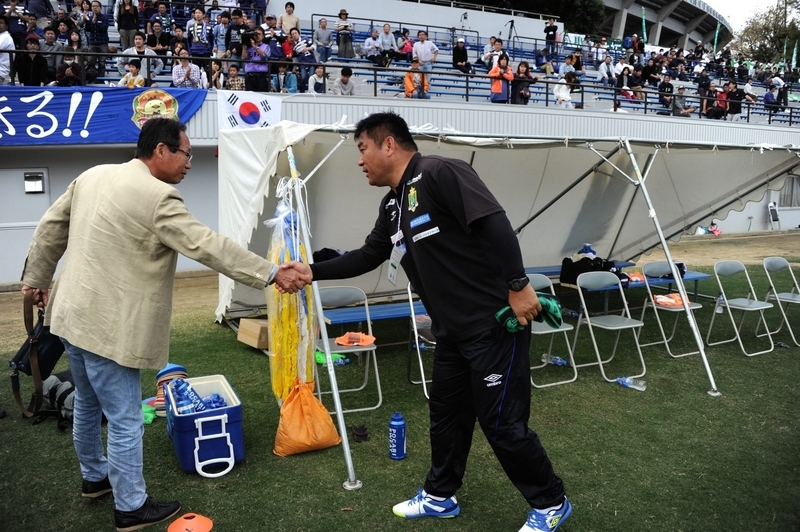 2015年の地域決勝1次ラウンドでの佐野達監督。FC今治との試合後、岡田武史会長と握手。