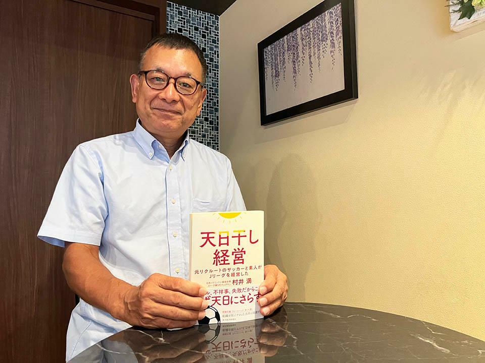 初の著書となる『天日干し経営』を手にする村井氏。あえてライターは起用せず、自分自身で執筆している。