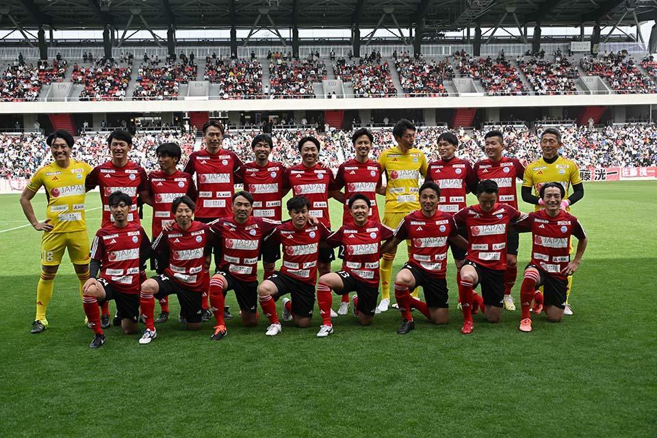 ツエーゲン金沢OBと石川県ゆかりのメンバーで構成されたチームがんばろう石川。新スタジアムでの集合写真に表情もほころぶ。