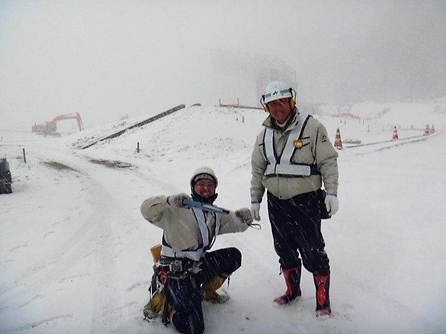 降雪の中、スタジアムの建設現場で作業に当たる石山さんら（本人提供）