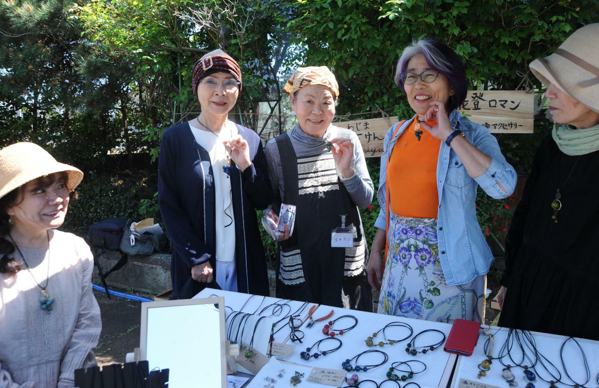 ブドウのペンダントを購入した客とともに。高木さん（左端）は、塩職人が輪島沖の海水から低温抽出した良質な苦汁を使った「わじま海石けん」も販売した