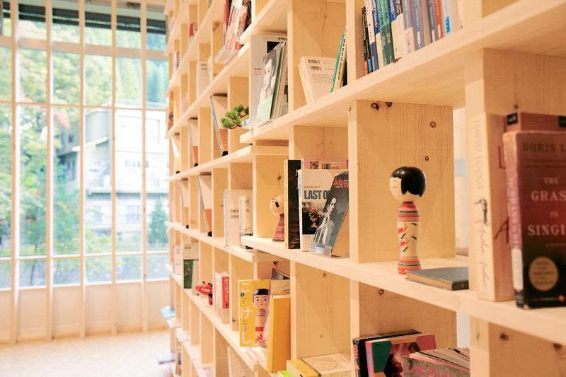 ロビーの書棚には旅の本がたくさん。こけしキャラクター「土湯きぼっこちゃん」も（写真提供YUMORI）