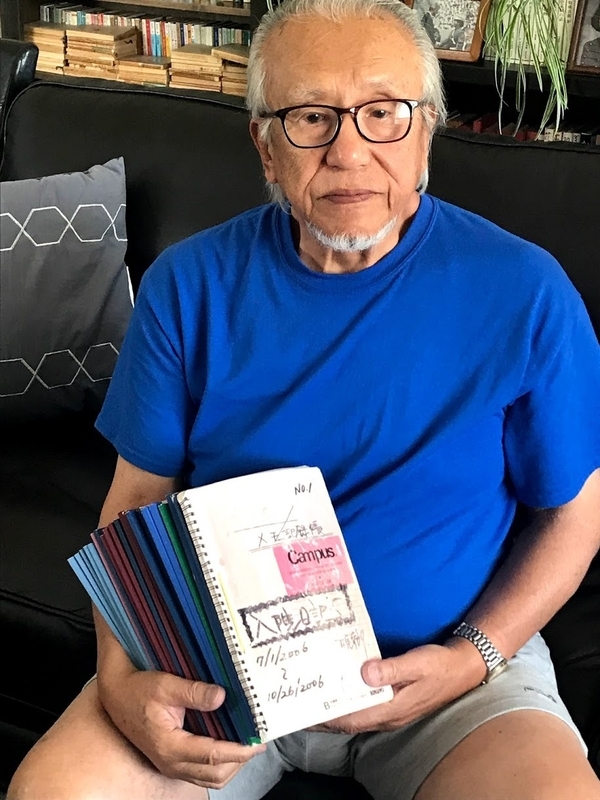 事故以来、毎日記録し続けた「入院日記」を手にする現在の松尾幸郎さん。25冊にのぼるこのノートは、夫妻の闘いの記録です(アメリカ・アルバカーキーの自宅にて筆者撮影）