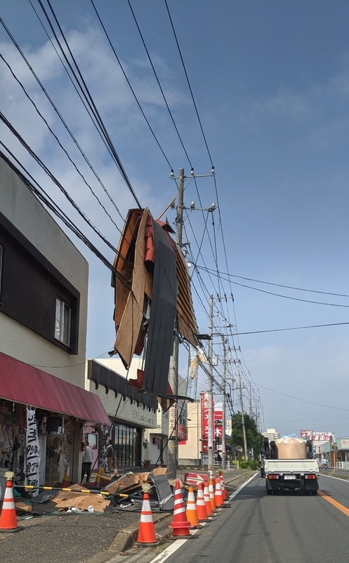 我が家から大網駅に向かう途中の道路わきの電線には、家屋から飛んできた大きな屋根の残骸がぶら下がっていました（筆者撮影）