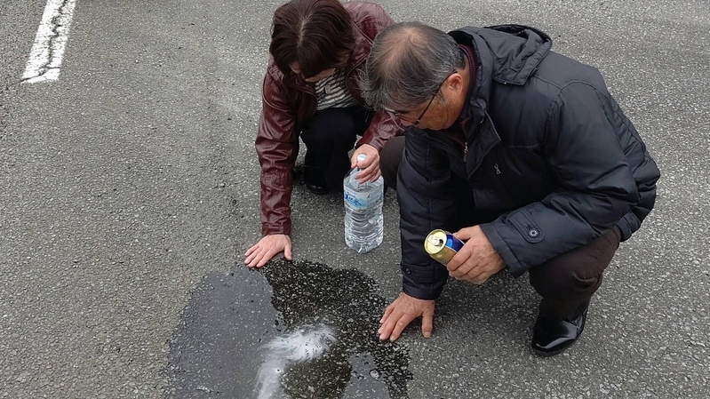 9年目のひき逃げ現場。血だまりのあった場所にビールと水を流す平野さん夫妻（平野さん提供）